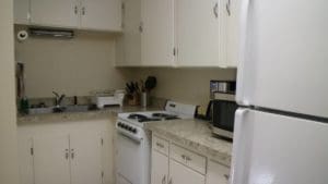 Kitchen with microwave, coffee maker and cooking range. Basin at the side