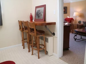 Sitting area on the corner with small table and three sitting chairs. Picture of an old car with red bottle on top of the table