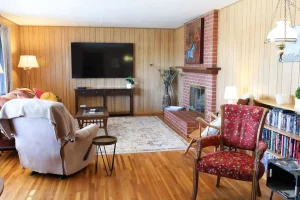 TV lounge with LCD screen on the wall with sofa and chair along rack