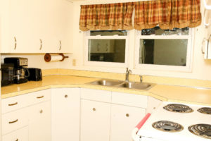 Kitchen sink, with cooking range and white cabinets and black coffee maker