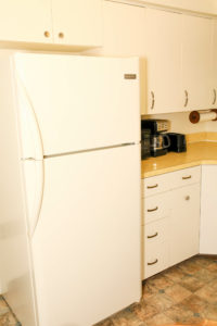 White fridge on kitchen with coffee maker and cabinets